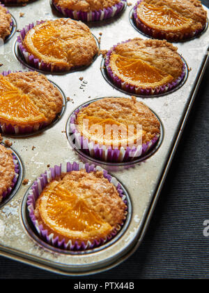 Fatti in casa muffin arancione in un rustico vassoio da forno. Foto Stock