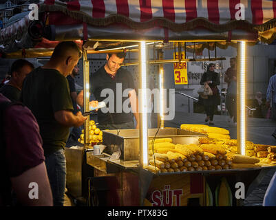 Istanbul, Turchia - 7 luglio 2018. Un venditore di stagionatura tutoli di mais in una bancarella di strada del quartiere Eminonu, un ex quartiere di Istanbul, Turchia, al tramonto. Foto Stock