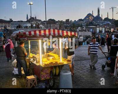 Istanbul, Turchia - 7 luglio 2018. I tutoli di mais in stallo in una strada del quartiere Eminonu, un ex quartiere di Istanbul, Turchia, con la Rustem Pasa Camii e Suleyma Foto Stock