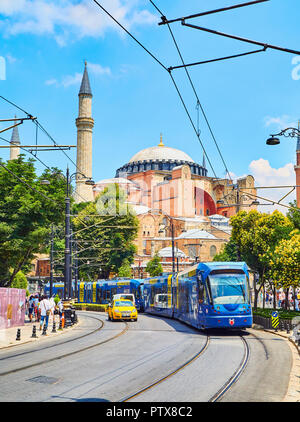 Istanbul, Turchia - 10 luglio 2018. Una fermata del tram e una corsa in taxi attraversando Divan Yolu Street con Hagia Sophia moschea in background. Istanbul, Turchia. Foto Stock