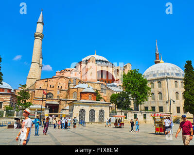 Istanbul, Turchia - 10 luglio 2018. I turisti a piedi nella parte anteriore dell'Hagia Sophia mosque a luce solare e una di pannocchie di granoturco in stallo in primo piano. Vista dal Foto Stock