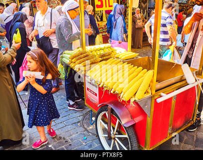 Istanbul, Turchia - 11 luglio, 2018. Una ragazza di acquistare un tutolo di mais ad una bancarella di strada del quartiere Eminonu, un ex quartiere di Istanbul, Turchia. Foto Stock