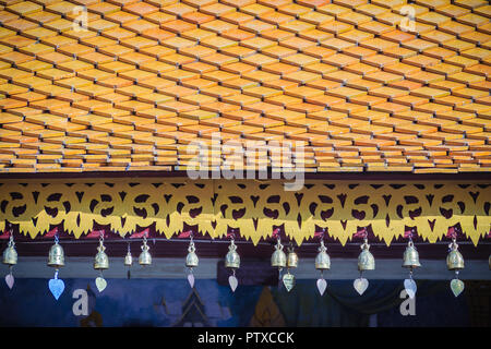 Bellissimo stile tailandese settentrionale del tempio di tegole del tetto e i dettagli di gronda con cute di piccole campane di bronzo. Decorativi in bronzo di piccole campane sono appesi al roo Foto Stock
