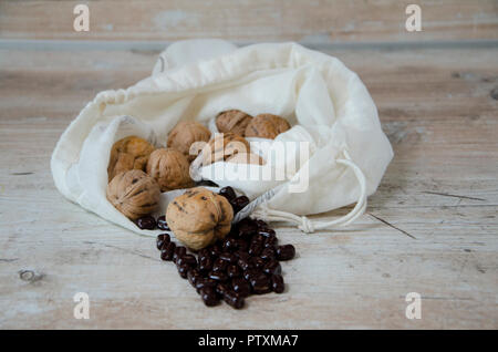 Le noci in un sacchetto con chicchi di cioccolato su un di legno tavolo da cucina Foto Stock