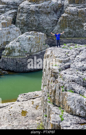 STUDEN KLADENETZ, Bulgaria - 2 Maggio 2015: maschio adulto in maglietta blu e cappello nero saluta mediante spalmatura di bracci su scogliere a Devil Canyon fenomeno naturale Foto Stock