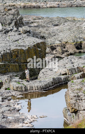 STUDEN KLADENETZ, Bulgaria - 2 Maggio 2015: femmina adulta in tourist vestiti guarda le foto scattate con il cellulare al diavolo Canyon fenomeno naturale un Foto Stock