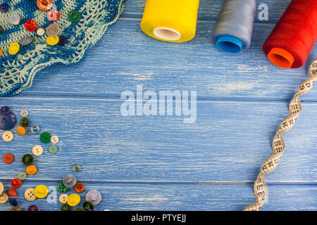 I thread e i pulsanti per centimetro di nastro su un blu sullo sfondo di legno Foto Stock