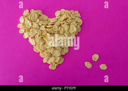 Cornflakes su uno sfondo rosa a forma di cuore Foto Stock