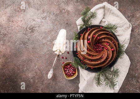 Gingerbread Bundt Cake per Natale con lingonberry e decorazioni di Natale su sfondo scuro, vista dall'alto Foto Stock