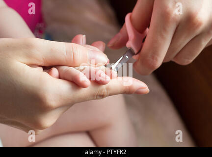 Una madre tagli i suoi chiodi ad un bambino, close-up Foto Stock