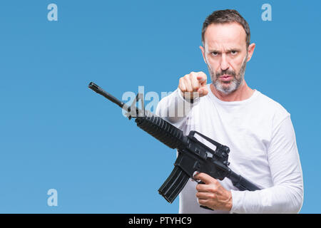 La mezza età senior annoso uomo delinquente tenendo la pistola arma più isolate di puntamento di sfondo con un dito alla fotocamera e a voi, mano segno, positivo un Foto Stock