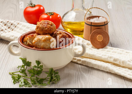 Fritte costolette di carne in ceramica Soup Bowl, pomodori rossi, bottiglia di vetro con olio di semi di girasole, sale in legno canna cantina, asciugatutto e del ramo freschi Foto Stock