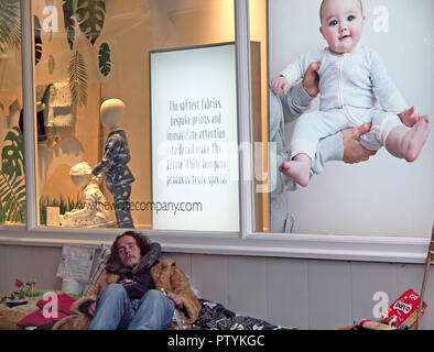 Un senzatetto uomo dorme davanti alla vetrina di un negozio display in Brighton Foto Stock