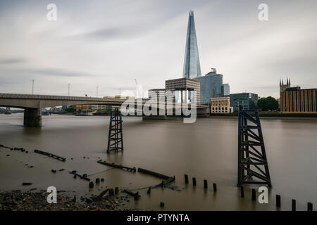 Una lunga esposizione di London Bridge e il Tamigi con il Coccio grattacielo in background su un nuvoloso giorno Foto Stock