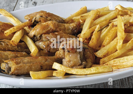Piatto ovale arrosto di ali di pollo con patate fritte al di sopra Foto Stock