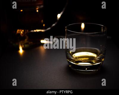 Un romantico, bassa immagine chiave di un bicchiere di whisky con alcune luci fairy in background Foto Stock