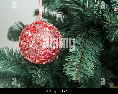 Rosso lucido sfera appesa su albero di Natale vicino fino Foto Stock