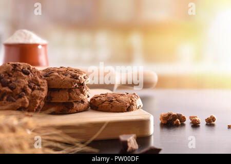 Biscotti fatti in casa con scaglie di cioccolato su legno nero tabella con ingredienti di una cucina rustica. Composizione orizzontale. Vista frontale Foto Stock