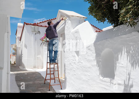 Andros, Grecia - 31 Maggio 2018: Greco Non identificato uomo parete vernici in cicladico tradizionale di colore bianco sull'isola di Andros, Cicladi Grecia Foto Stock