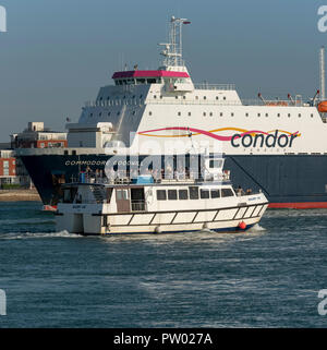 Commodore buona volontà un canale trasversale nave commerciale inserendo il porto di Portsmouth, England Regno Unito. In attendace un tour del porto con imbarcazione di passeggeri Foto Stock