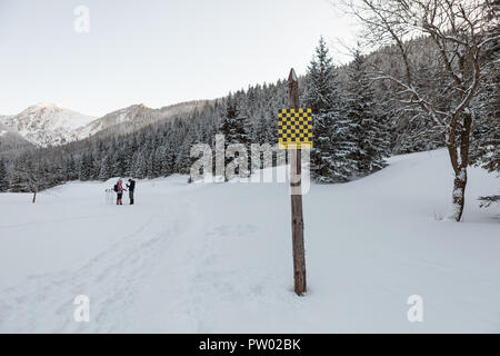 Area di valanghe di cartello di avviso in lingua inglese e in lingua polacca, nella valle dei monti Tatra, Inverno tempo Foto Stock
