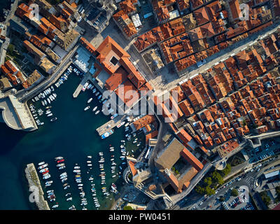 Soleggiata cityscape di vecchia Dubrovnik con case con tetti incastrata, le chiese, le mura di fortificazione e un molo con molti yacht e barche. Le persone sono Foto Stock