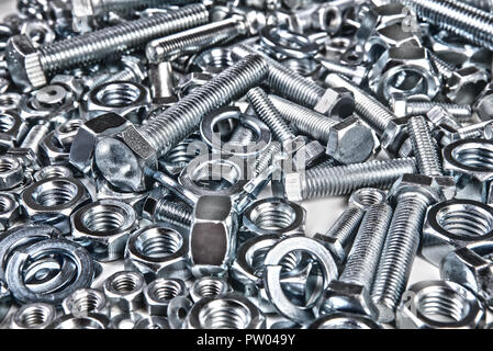 Chromeplated bulloni e dadi su sfondo bianco Foto Stock