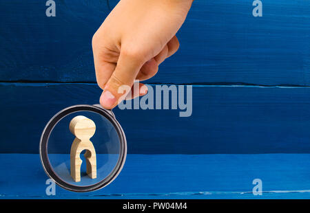 Lente di ingrandimento è guardando la figura di legno di una donna con un vuoto all'interno nella forma di un bambino. Il concetto di perdita del bambino, l'aborto di Foto Stock