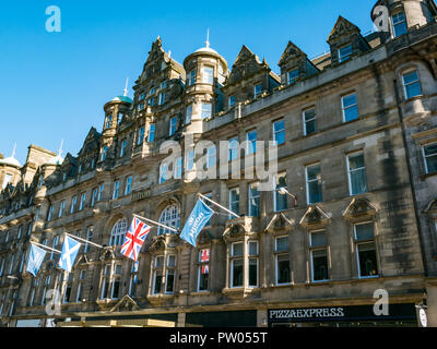 Grandi scozzesi stile baronale Palazzo signorile ora Hilton Carlton Hotel, con Pizza Express segno, North Bridge, Edimburgo, Scozia con le bandiere Foto Stock