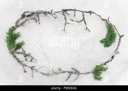 Cornice fatta di ramoscelli di muschio verde e rami di pino, su sfondo di calcestruzzo. Natura nordica. Foto Stock