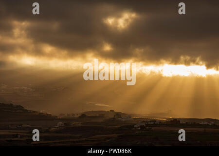 La mattina presto i raggi del sole attraverso la rottura di un divario tra le nuvole illuminando i villaggi di collina nella municipility di Guia de Isora, Tenerife, Canarie ho Foto Stock