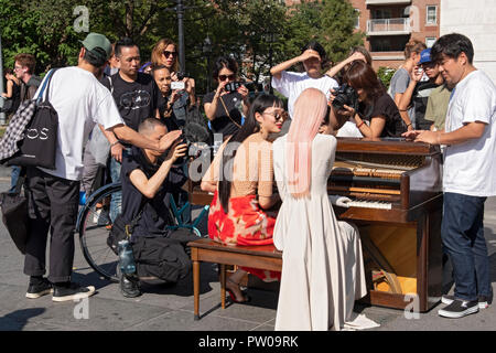 Due belle sottili modelli giapponesi, i fotografi, Entourage e curiosi di Washington Square Park nel Greenwich Village di New York City. Foto Stock