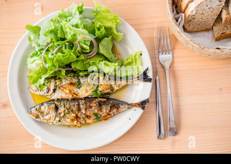 Due appena le Sardine alla brace servite con insalata di lattuga e pane Foto Stock