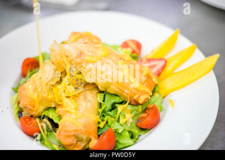 Mare crocchette di cibo servito con lattuga, pomodori ciliegini e mango sulla piastra bianca Foto Stock