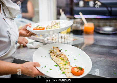 Golden filetto di pesce con pomodoro e coriandolo portato dal cuoco nel ristorante Foto Stock