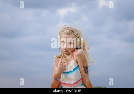 Adorabile bambina con capelli biondi ritratto e cielo blu Foto Stock