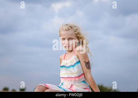 Adorabile bambina con capelli biondi ritratto e cielo blu Foto Stock