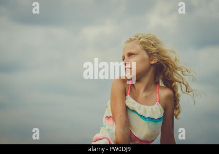 Adorabile bambina con capelli biondi ritratto e cielo blu Foto Stock