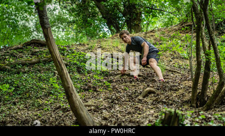 Il ragazzo è in esecuzione su per una collina ripida durante la partecipazione a una gara di ocr Foto Stock