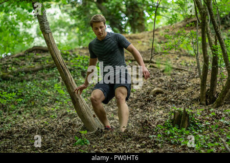 Il ragazzo è in esecuzione su per una collina ripida durante la partecipazione a una gara di ocr Foto Stock