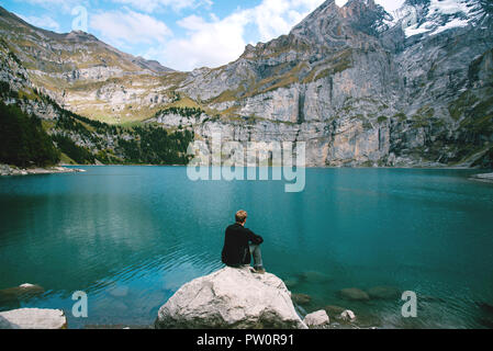 Escursionista guardando alla vista del lago Oeschinen nelle alpi svizzere con belle acque turchesi. La natura e i concetti di viaggio. Foto Stock
