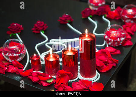 Decorato con candele rosse e petali di colore rosso. Perla Foto Stock