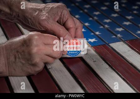 Rotolo di ho votato oggi gli adesivi di carta su di noi bandiera con la mano la rimozione di uno Foto Stock