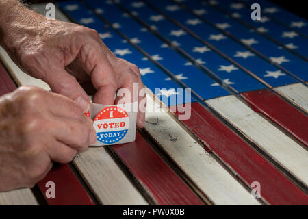 Rotolo di ho votato oggi gli adesivi di carta su di noi bandiera con la mano la rimozione di uno Foto Stock