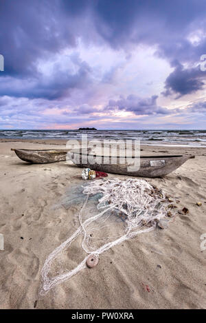 Barca e rete da pesca nella sabbia della spiaggia durante la tempesta il tramonto sul lago Malawi Kande Beach in Africa, pescatore del pesce net Foto Stock