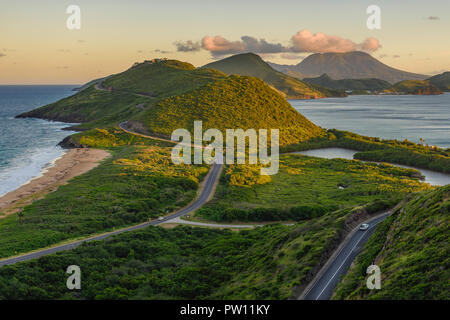 Saint Kitts montagne e punto di vista mare e vista delle strade per il sud dell'isola dei Caraibi durante il tramonto. Oceano blu e verdi lussureggianti montagne mi Foto Stock