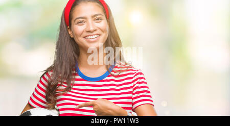 Giovane bella donna araba holding soccer football palla su sfondo isolato molto felice puntando con mani e dita Foto Stock