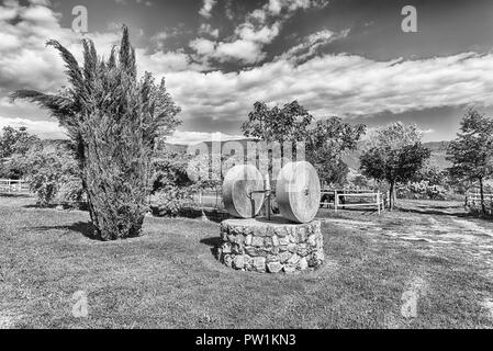 Antico frantoio con due macine in campagna Foto Stock