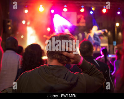 Lonely Giovane triste in mezzo alla folla guardando un concerto, la mano sulla testa. Foto Stock