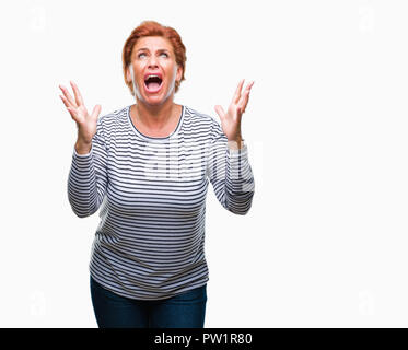 Accattivante senior redhead caucasica donna sullo sfondo isolato e pazzo pazzo grida e urla con espressione aggressiva e bracci sollevati. Le unità FRU Foto Stock